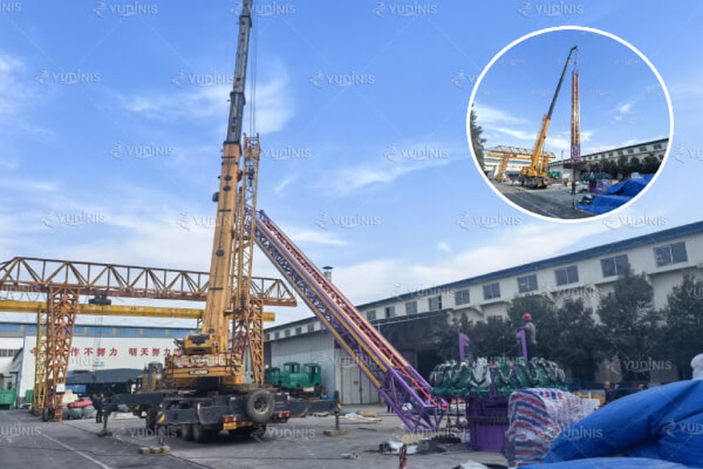 crane lifting a drop tower during installation on site